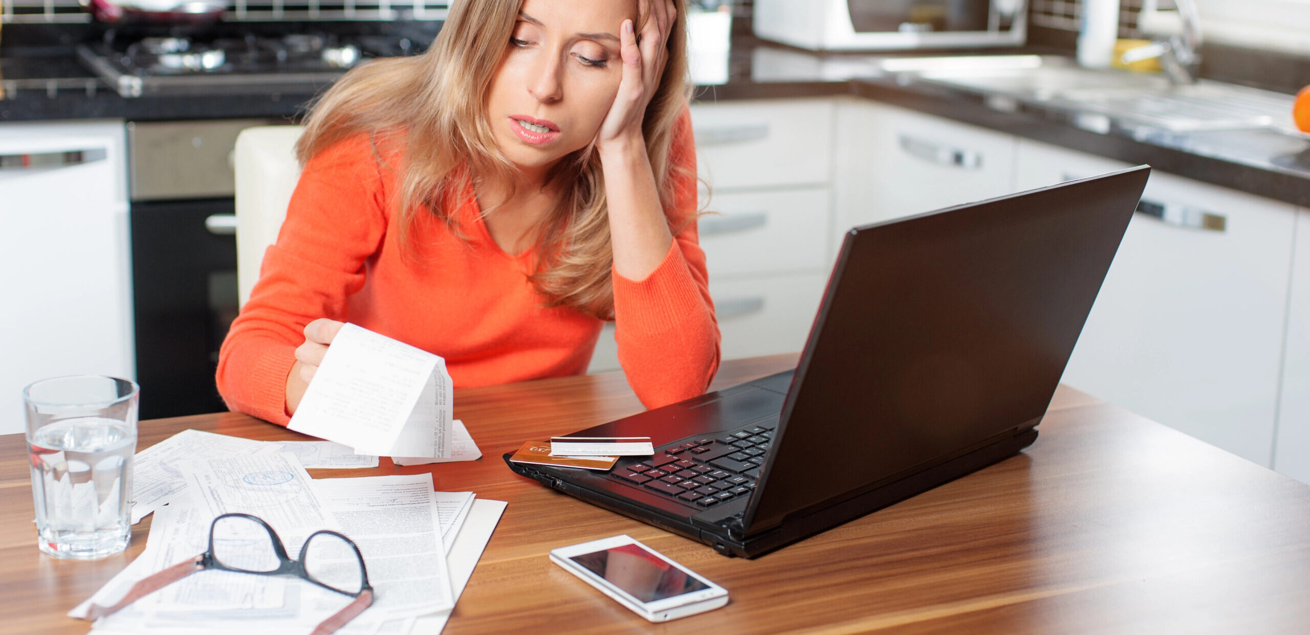 Worried woman checks bills and laptop for energy charges at kitchen table UK workplace discrimination claims