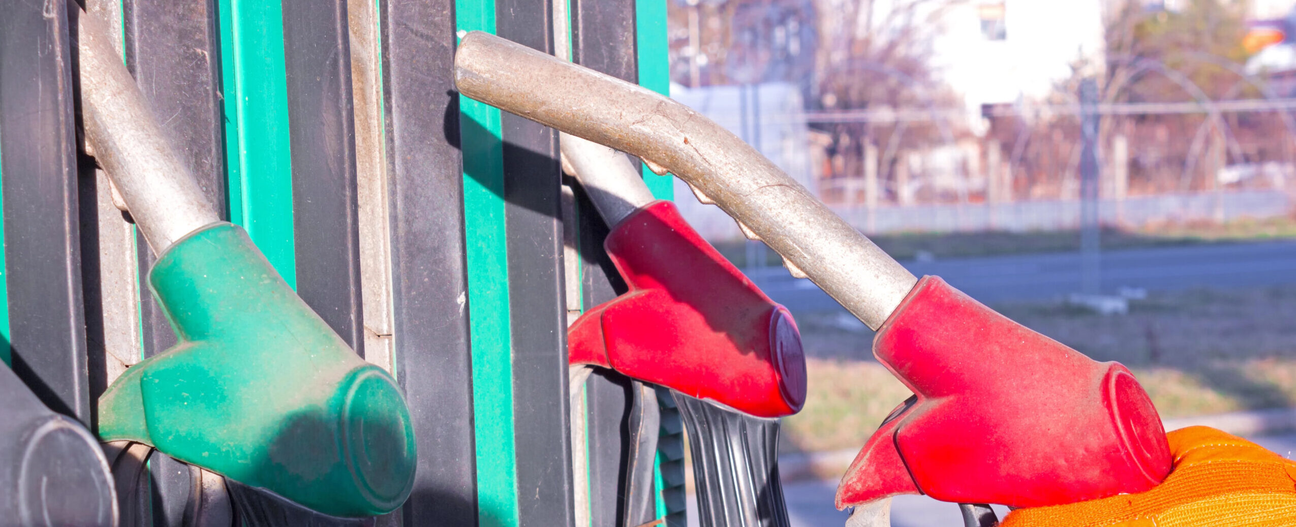 Gloved hand picking a diesel fuel nozzle among several pump options