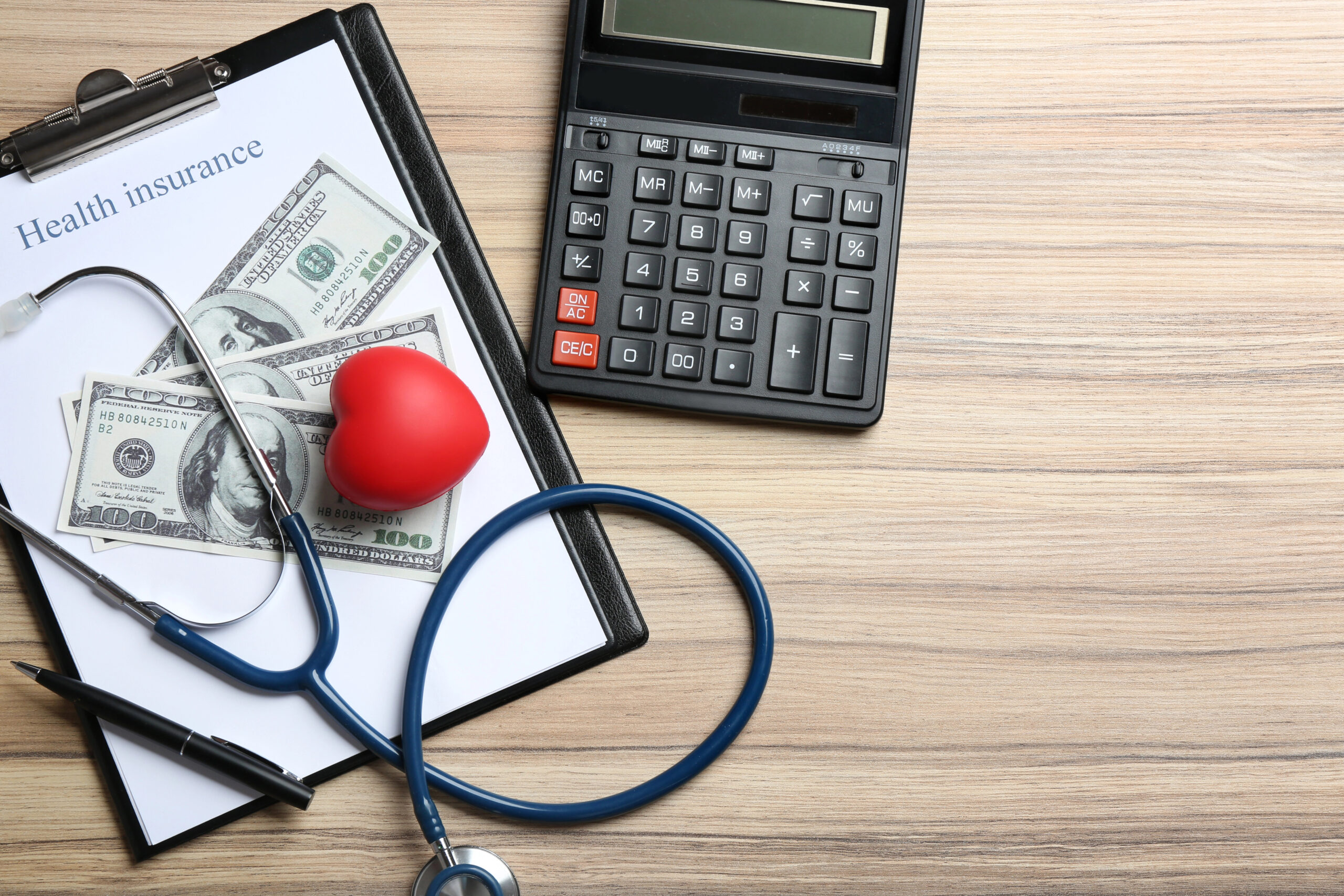 Health insurance with calculator and dollar bills on clipboard
