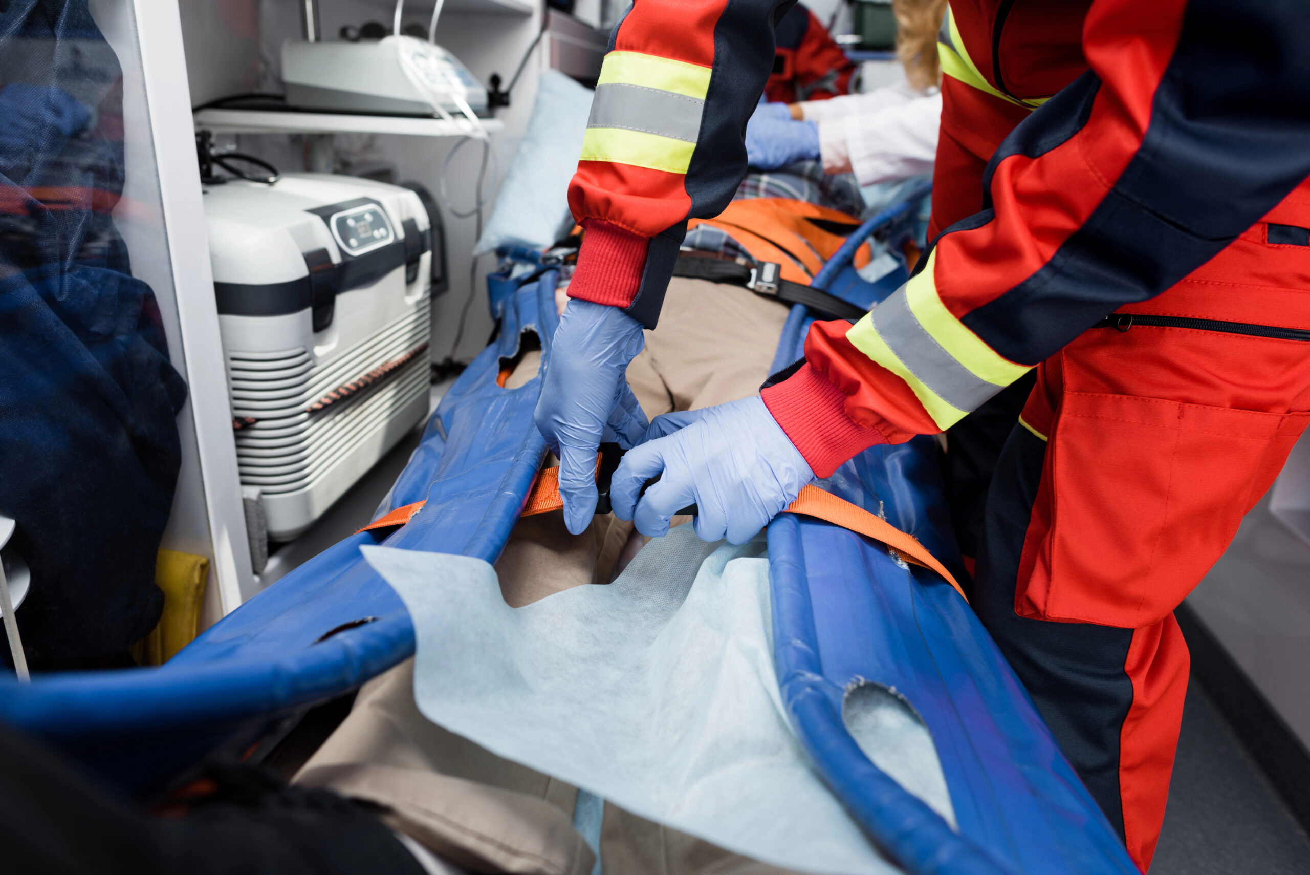 Paramedics securing an injured worker on a stretcher inside an ambulance