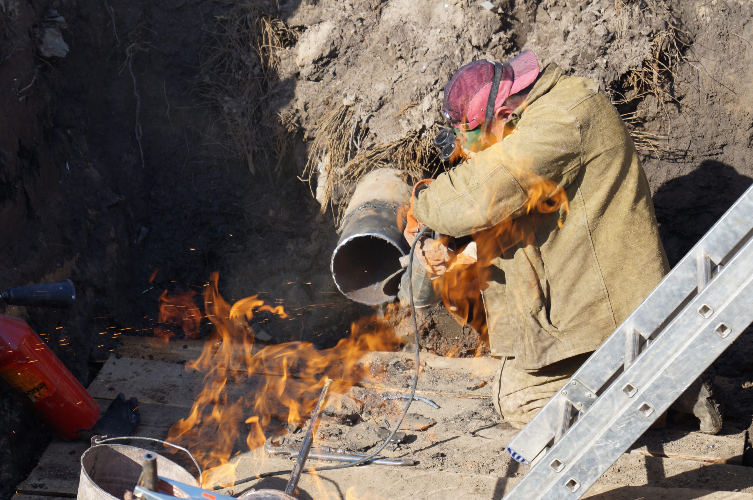 Worker in protective gear surrounded by fire during welding operation