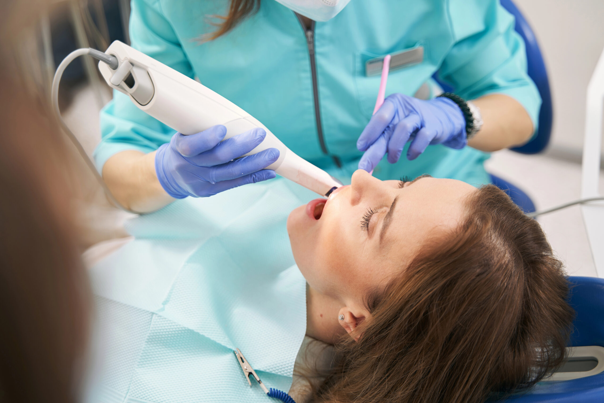 Close-up of an intraoral scanner with patient in background